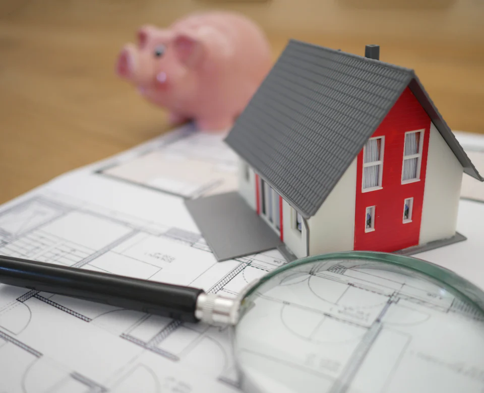 Model house with property plans and a magnifying glass